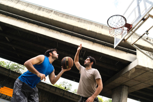 Δύο καυκάσιοι άνδρες pratice baskegball στο δικαστήριο στο αστικό δρόμο. - Φωτογραφία, εικόνα