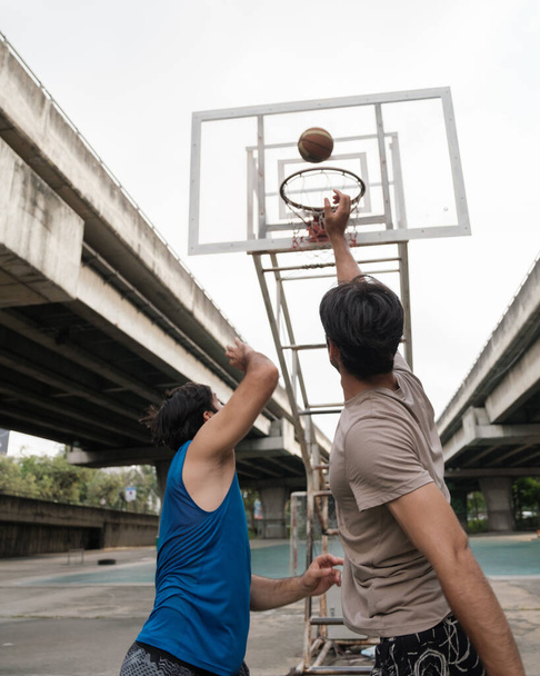 Двое кавказских мужчин практикуют баскетбол в суде на городской улице. - Фото, изображение
