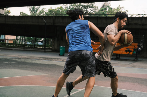 Dos hombres caucásicos pratice baskegball en corte en la calle urbana. - Foto, Imagen