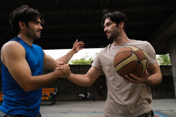Twee blanke mannen oefenen basketbal in de rechtbank op Urban Street.. - Foto, afbeelding