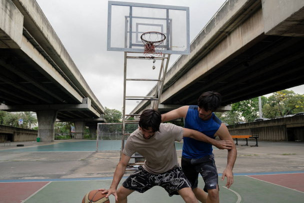 Kaksi valkoihoista miestä pratice koripallo oikeudessa kaupunkien kadulla. - Valokuva, kuva