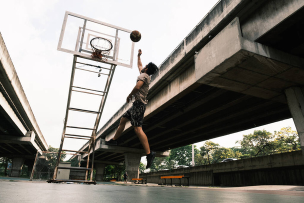 Joven jugador de baloncesto causian tiro pelota en la calle cancha. - Foto, Imagen