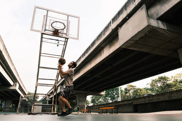 Young causian basketball player shooting ball on street court. - Φωτογραφία, εικόνα