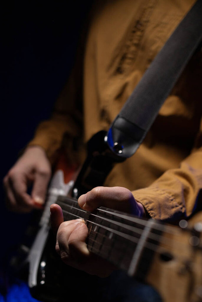 Elektromos gitáros férfi. Zenész a stúdióban elektromos gitár közel fal - Fotó, kép