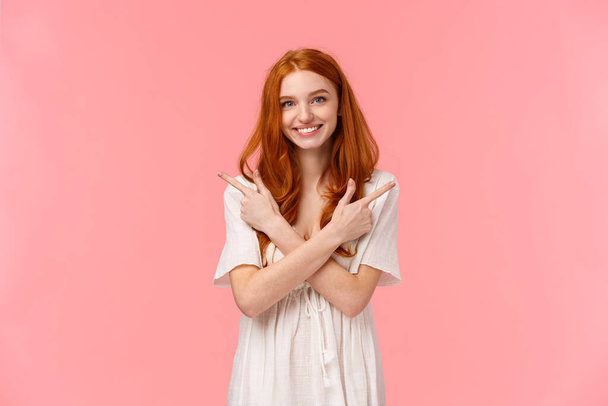 Waist-up portrait lovely feminine, sensual redhead woman in white dress, asking your opinion, showing two variants, cross hands over body and pointing left and right banners, smiling friendly. - Фото, зображення
