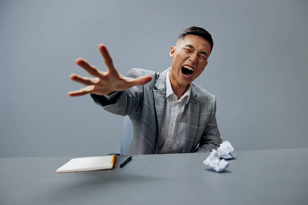 Aasialainen mies harmaassa puvussa rypistynyt paperi toimisto virallisia tunteita eristetty tausta. Laadukas kuva - Valokuva, kuva