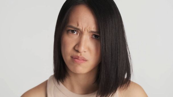 De cerca mujer asiática ofendido en novio mirando enojado en cámara aislada sobre fondo blanco. Expresión facial iracunda - Foto, Imagen