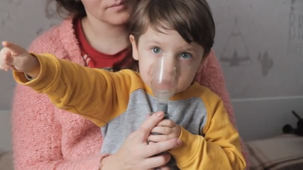 Tratamiento de los pulmones y las vías respiratorias en niños. El bebé está siendo tratado con un inhalador. Madre trata al bebé en casa con un inhalador. - Metraje, vídeo