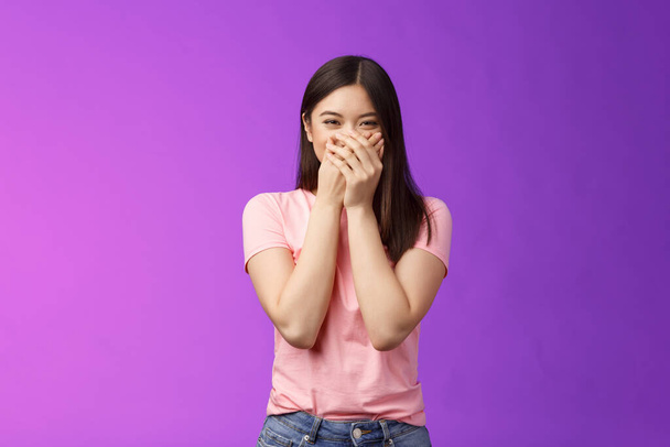 Cute carefree happy young asian girlfriend fooling around, giggle, close mouth palms not laugh loud, acting silly childish, joking, blushing receive surprising cute present, stand purple background. - Photo, Image