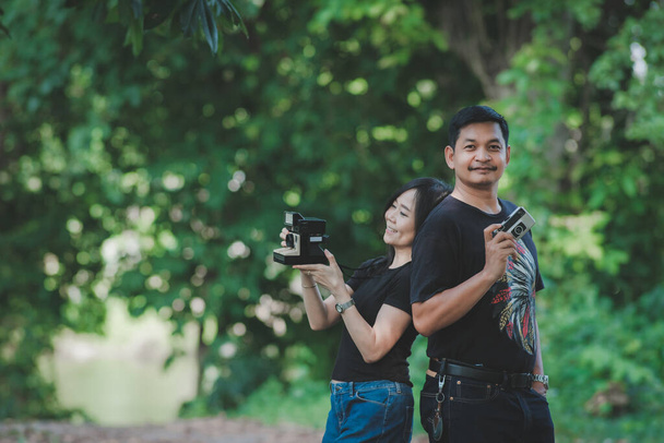 Een stel leert om foto 's te maken met vriend die zijn vriendin leert over fotografie in het bos of park - Foto, afbeelding