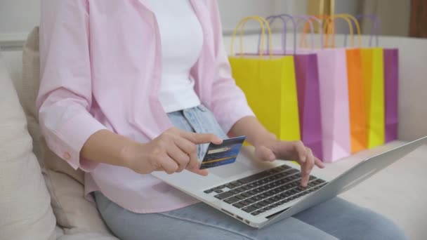 Dłonie kobiety siedzącej na kanapie korzystającej z laptopa zakupy online z karty kredytowej zakupu do Internetu, szczęścia dziewczyny płacącej transakcji finansowej, zakupu i płatności, koncepcja biznesu. - Materiał filmowy, wideo
