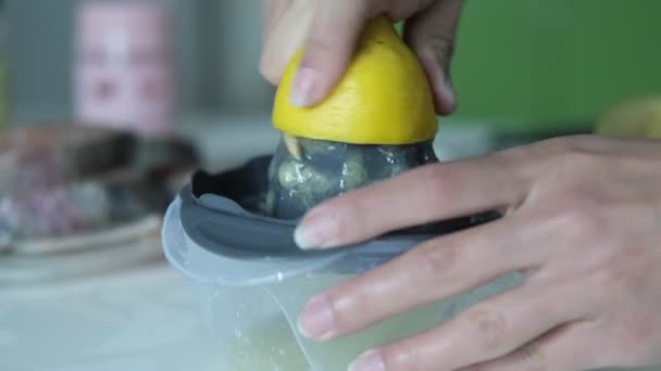 Beelden van het proces van het extraheren van citroensap door het spinnen in een citroenpers, close-up weergave van het persen van citroensap, beeld van het sap van een gele citroen op een witte achtergrond - Video