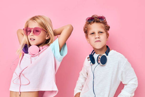 funny little boy and girl blonde hair fashionable glasses pink color background. High quality photo - Photo, Image
