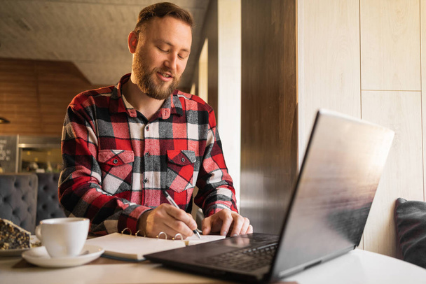 бизнесмен, работающий с документами и ноутбуком в кафе, случайный человек фрилансер в кофейне, планирующий в бизнесе, работающий онлайн концепция - Фото, изображение