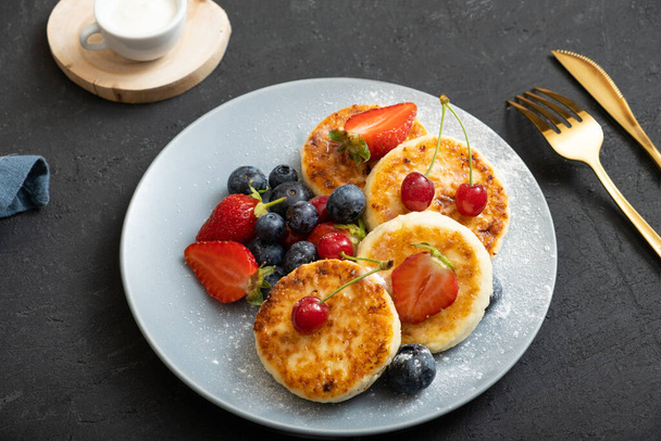 Roasted cheesecakes on a plate with powdered sugar and berries angle view. - Φωτογραφία, εικόνα