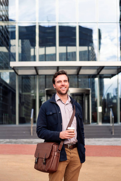 hombre de negocios feliz con un café frente a la entrada del edificio de oficinas, concepto de trabajo y estilo de vida, espacio de copia para el texto - Foto, imagen