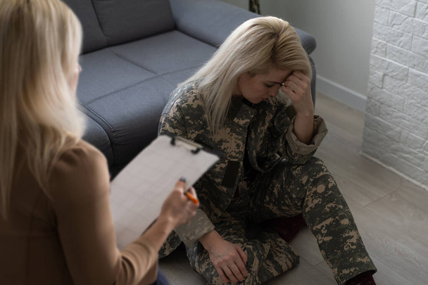 Психолог робить нотатки під час терапії з солдатом (ПТСР).. - Фото, зображення
