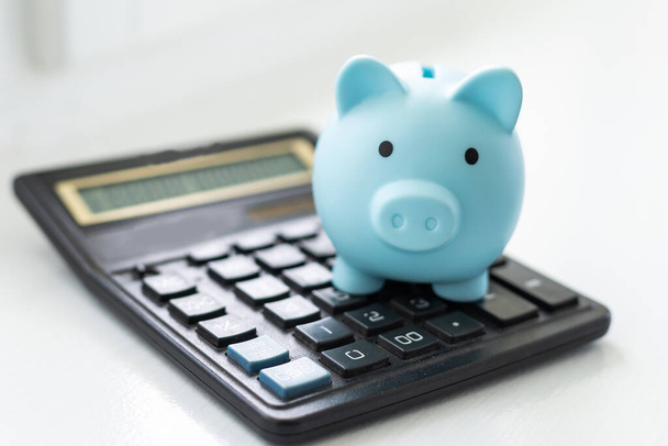 Piiggy bank avec calculatrice close-up sur fond bleu pastel. Calcul du budget familial, épargne. Minimalisme - Photo, image