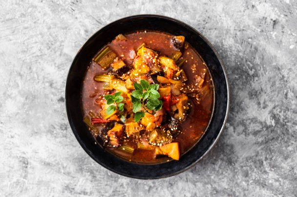 vegán török forró edény padlizsán zellerrel és burgonyával fűszeres levesben vegyes fűszernövényekkel, egészséges növényi alapú ételreceptek - Fotó, kép