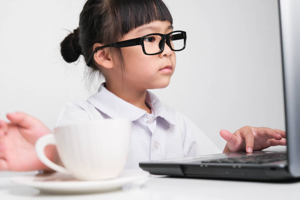 Little businesswoman with laptop working in office with coffee cup on table. children and business concept. - Foto, Imagen