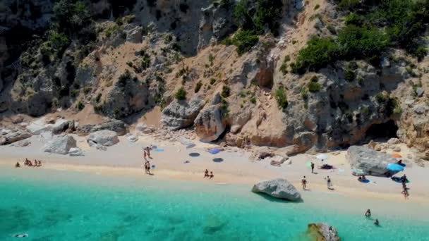 Golfo di Orosei Sardina, yukarıdan manzara, plaj şemsiyeleriyle dolu bir plaj manzarası ve turkuaz suda güneşlenen ve yüzen insanlar. Cala Gonone, Sardinya, İtalya, Cala Mariolu. - Video, Çekim