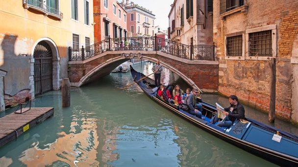 Tourists enjoying a tour on gondola in Venice. - Фото, изображение