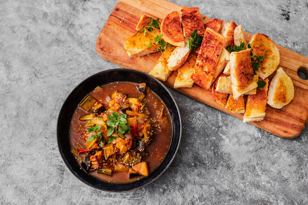 vegan turkish hot pot with eggplant celeri and potaotes in spicy broth with garlic bread, healthy plant-based food recipes - Fotografie, Obrázek