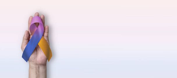 Blaas kanker bewustzijn lint met goudsbloem paarse blauwe strik op de hand ondersteuning op kleur achtergrond met kopieerruimte - Foto, afbeelding
