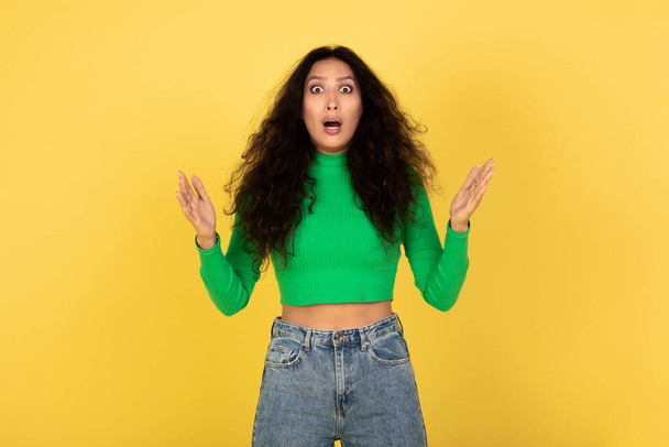 Omg, No Way. Portrait of excited surprised and amazed young lady looking at camera with open mouth and spreading hands, shocked woman cant believe her eyes, isolated over yellow studio background - Фото, изображение