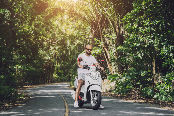 Stylish young man and his motorbike on the road in the jungle. - Foto, Bild