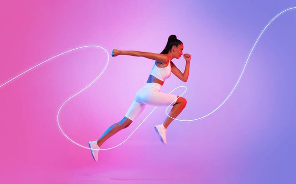 Sporty Female Runner With Neon Light Line Running In Mid Air Looking Aside Over Pink And Blue Studio Background. Sportswoman Runs Wearing White Fitwear. Sport And Fitness Concept. Side View - Foto, immagini