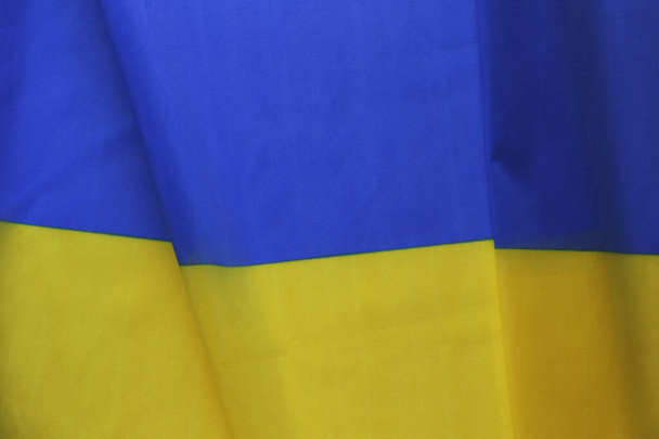 Close up shot of ruffled Ukrainian yellow and blue flag with a lot of copy space for text. Textured background. - Φωτογραφία, εικόνα