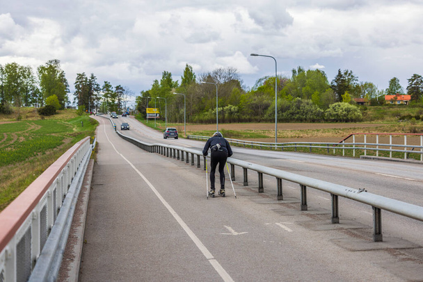 Man trains on roller skis on dedicated bike path on summer day. Sweden. - Φωτογραφία, εικόνα