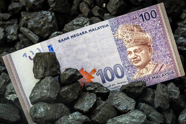 Malezyjskie pieniądze wystające z węgla, 100 ringgit banknot Górnictwo i górnictwo koncepcja w Malezji, Rosnące ceny węgla, Wpływ na środowisko, Przemysł i gospodarka kraju - Zdjęcie, obraz