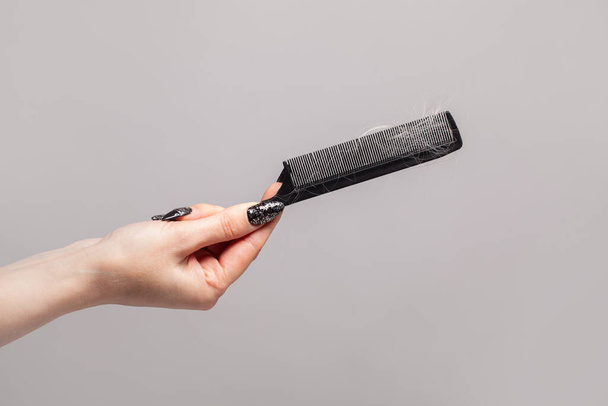 Female hand holding comb with hairs - Foto, Imagen