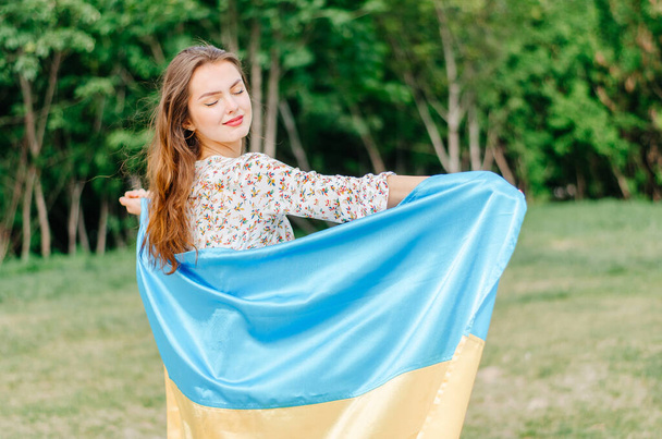 Ukrajinská žena s vlajkou Ukrajiny. Dívka s vlajkou Ukrajiny. Ukrajinská vlajka. Ukrajina. Vlastenecká fotografie dívky s modrou a žlutou vlajkou Ukrajiny - Fotografie, Obrázek