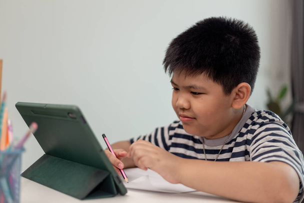 かわいいアジアの子供は自宅でタブレットからビデオ通話でオンライン学習クラスを学びます。 - 写真・画像