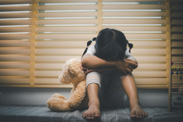 Közelkép magányos kislány ölelés játék, ül otthon egyedül, ideges boldogtalan gyermek várja a szülőket, gondolkodás problémák, rossz kapcsolat a családban, pszichológiai trauma - Fotó, kép