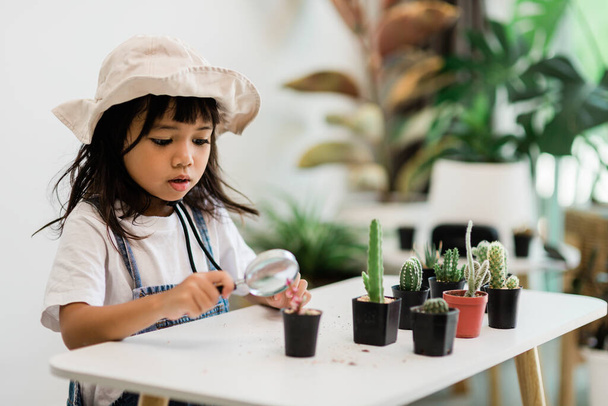 kid gently touch new stem of the cactus he grows with care, one hand holds magnifying glass.Nature education, Montessori and observation skills concept. - Фото, зображення