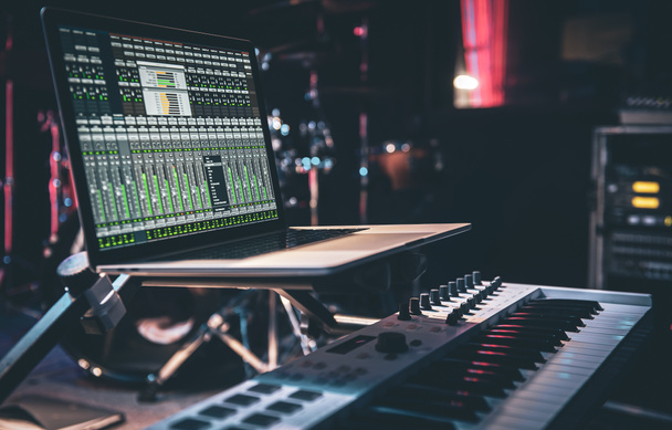 Modern zenei stúdió vezérlő asztal laptop képernyőn mutatja a digitális audio állomás szoftver felhasználói felület. - Fotó, kép