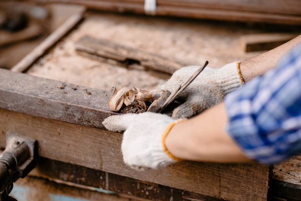 closeup mannelijke houtbewerker hand gesneden scheerhout hout met hout scheergereedschap voor het maken van meubels - Foto, afbeelding