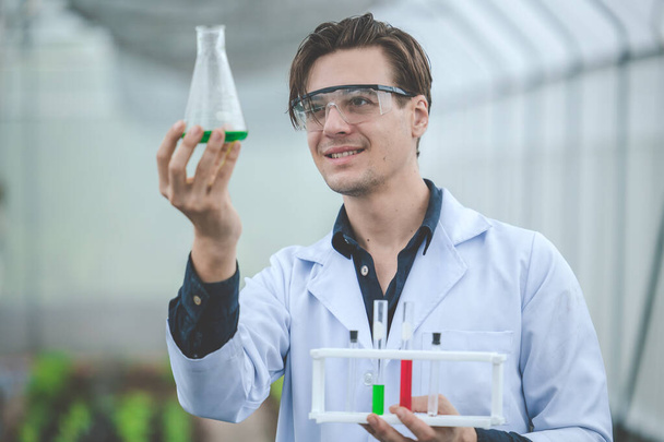 Bio-Wissenschaftler in der Landwirtschaft glücklich lächeln Blick auf neue chemische Formel Probe Extrakt aus Pflanzenfarm-Konzept. - Foto, Bild