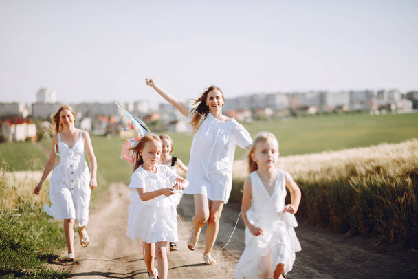 Family in a autumn field. Mother in a white dress. Cute little girls - Zdjęcie, obraz