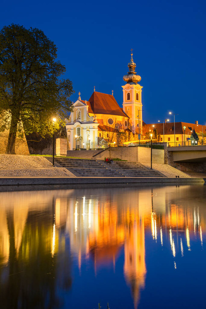 Gyor, city in Hungary,  baroque Carmelite church by night reflecting in Raba river - Photo, Image