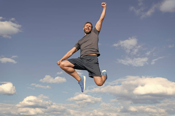 homme musclé sautant en vêtements de sport en plein air sur fond de ciel, succès. - Photo, image