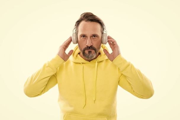 serieuze volwassen man met baard en snor in hoody luisteren muziek of audio boek in koptelefoon geïsoleerd op wit, modern onderwijs. - Foto, afbeelding
