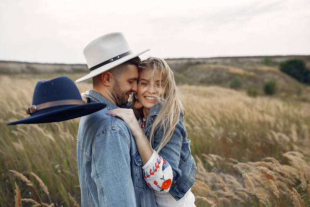Loving couple in a wheat field. Beautiful blonde in a blue hat. - Fotografie, Obrázek