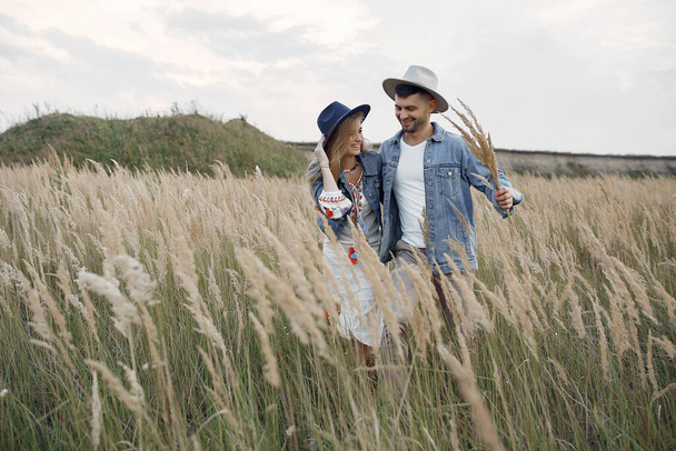 Loving couple in a wheat field. Beautiful blonde in a blue hat. - Valokuva, kuva
