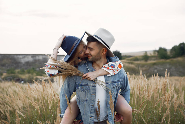Loving couple in a wheat field. Beautiful blonde in a blue hat. - Φωτογραφία, εικόνα