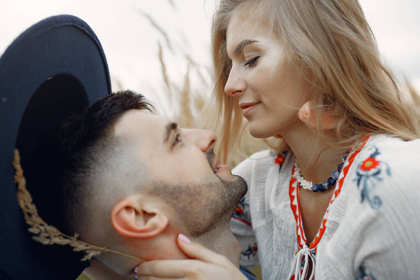 Loving couple in a wheat field. Beautiful blonde in a big earrings - Foto, imagen